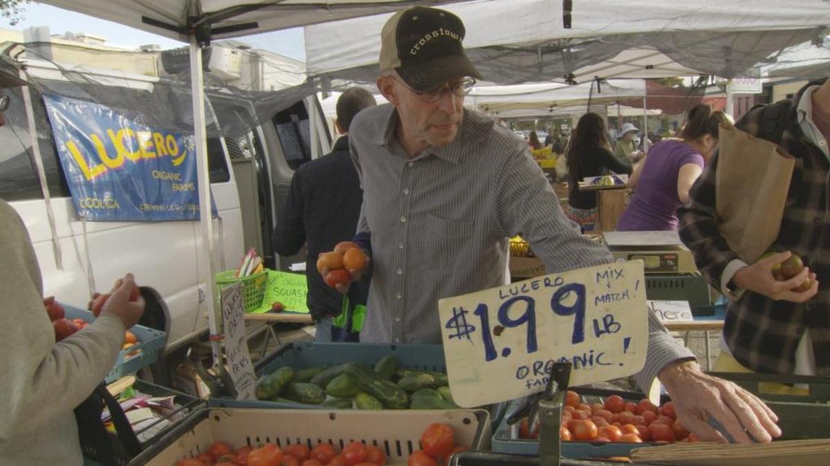 Michael Pollan shops for vegetables at a farmers market.