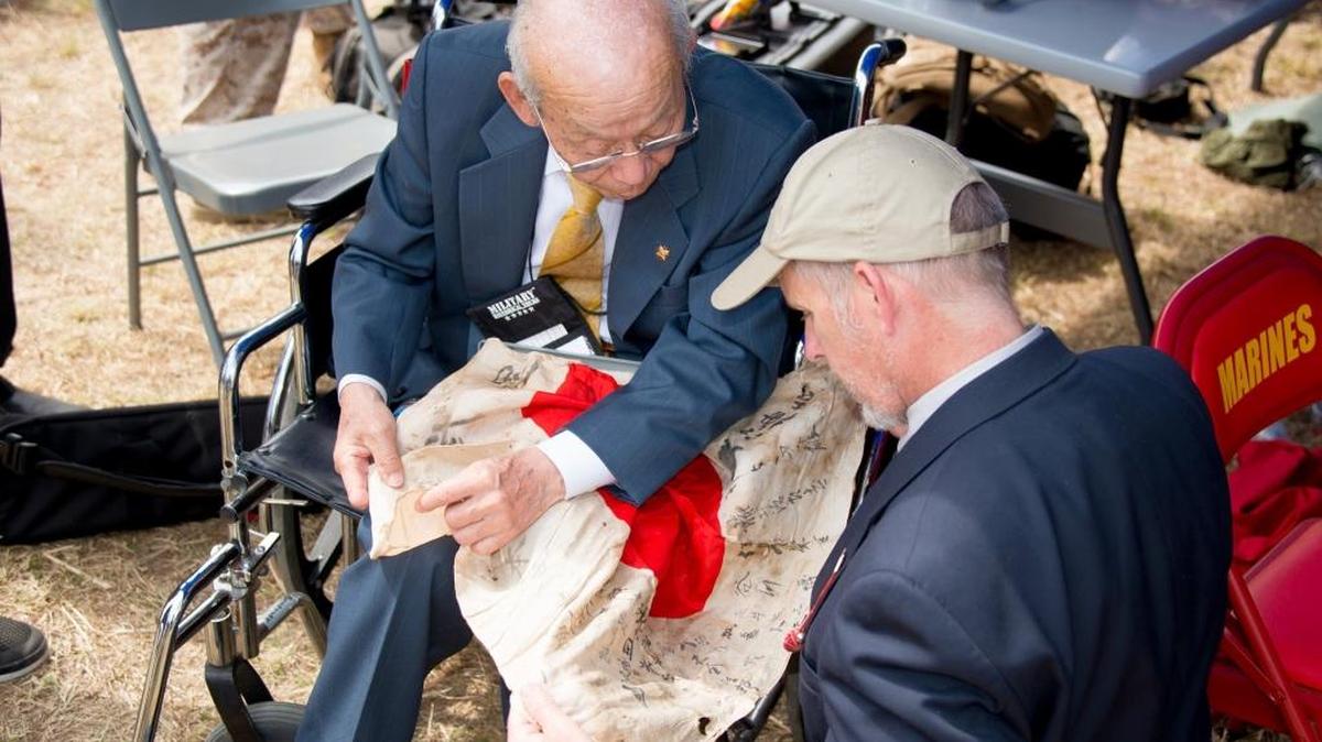 Japanese veteran Tsuruji Akikusa (left), with Dan King (right), author of “A Tomb Called Iwo Jima,” holding a Japanese flag that had been brought back to the U.S. as a souvenir during WWll. Mr. Akikusa was able to locate the family of the man to whom it belonged.