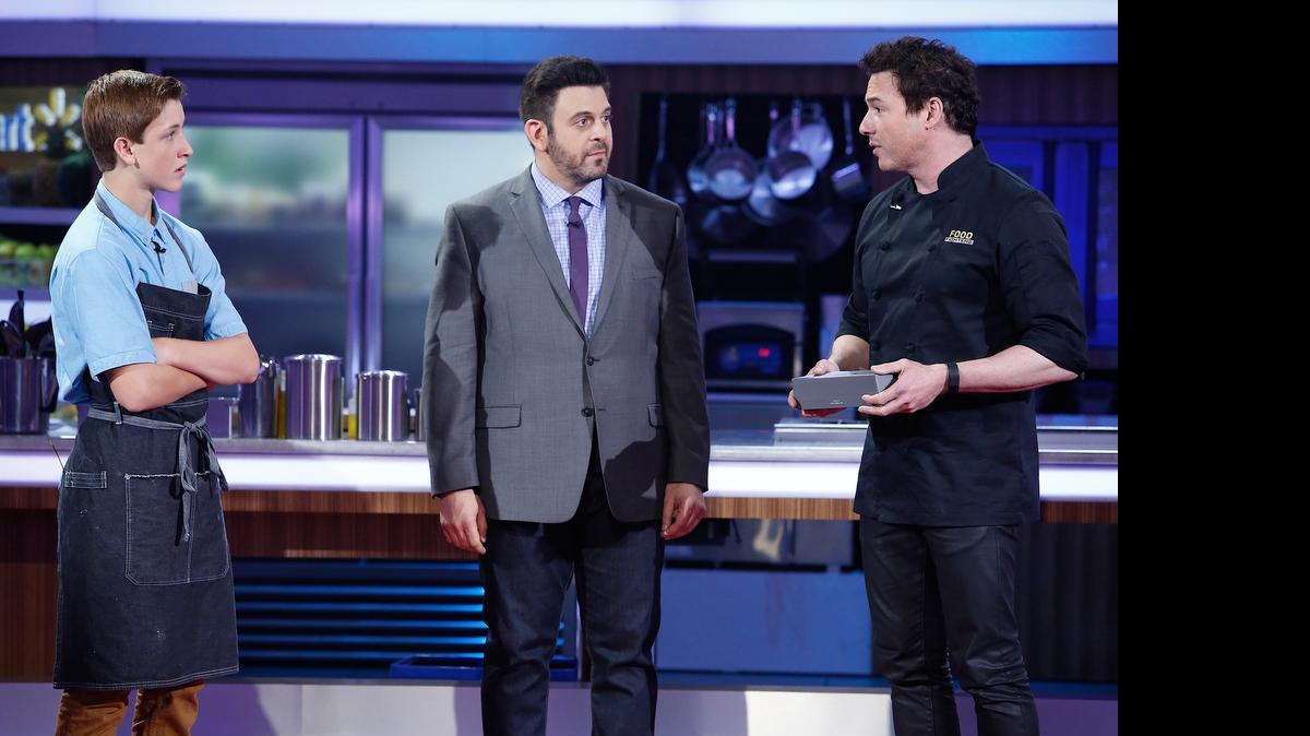 
Troy Glass (left) will compete on the first season of “Food Fighters,” a new reality competition show on NBC hosted by Adam Richman (center). Chef Rocco Dispirito at far right.

