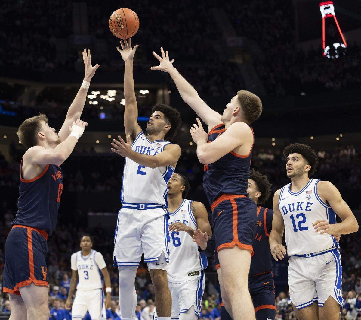 Duke guard Cayden Boozer (2) puts up a shot against Virginia center Johann Grunloh (17) and forward Thijs De Ridder (28) in the first half .