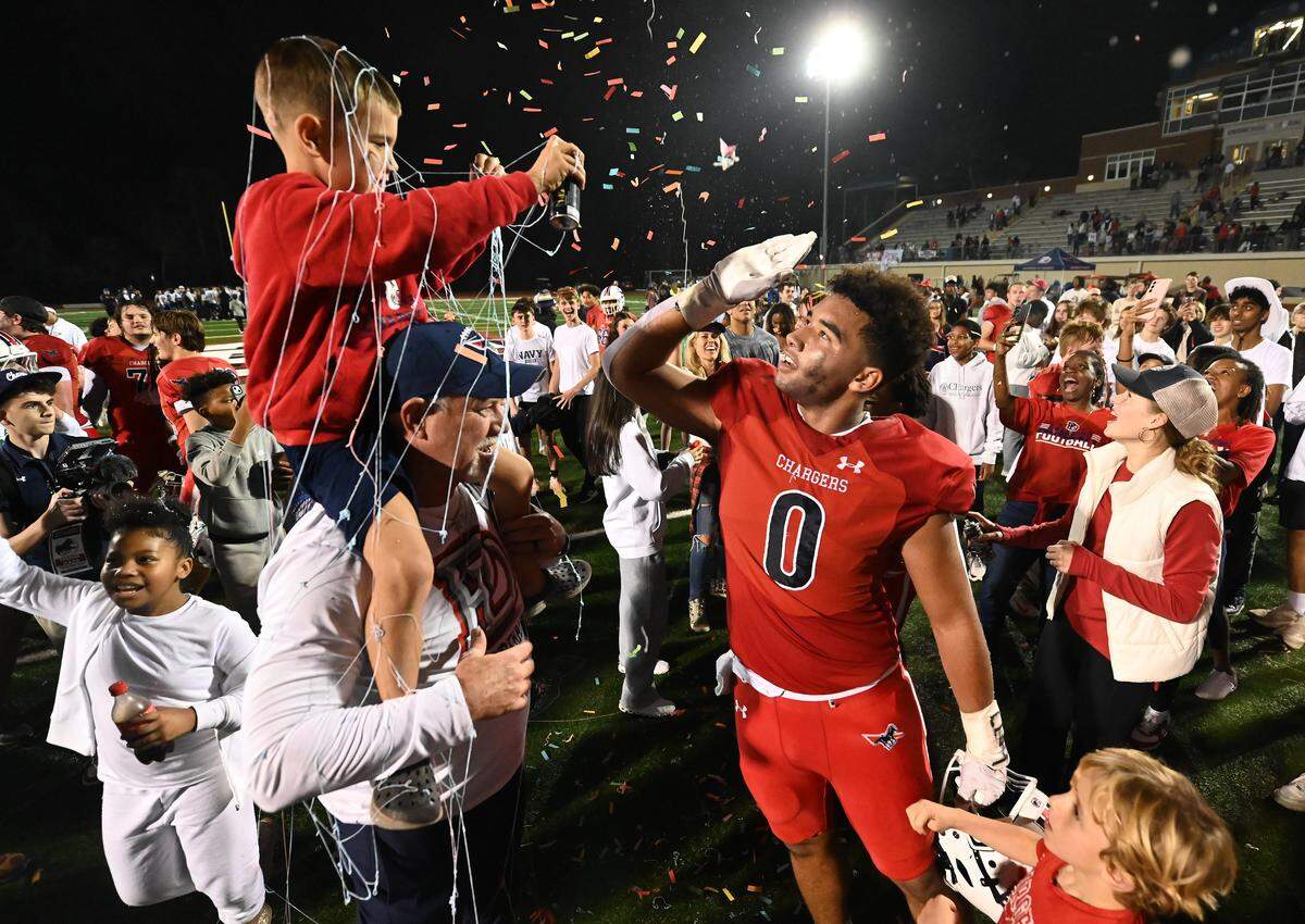 Providence Day Chargers head coach Chad Grier, left and son Hank, celebrates the team’s victory over Charlotte Christian in the NCISAA D1 state championship game with Griff Galloway, right, on Friday, November 21, 2025. Providence Day defeated Charlotte Christian 42-6.