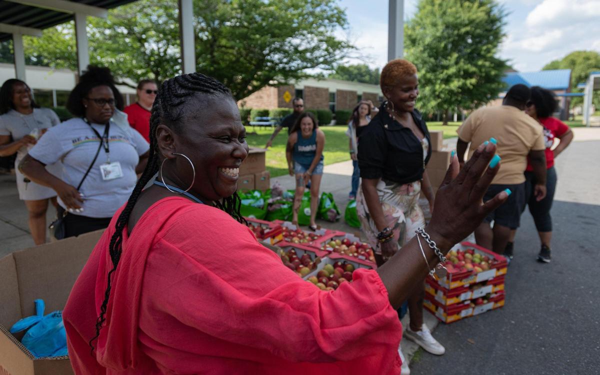 LaTonya Wallace, a teacher at Westerly Hills Academy and on site coordinator of Above & Beyond Students, sends off cars with smiles and waves as Charlotte-Mecklenburg Schools hosts a mobile pantry with donated items from Second Harvest Food Bank of Metrolina Tuesday night in Charlotte. Bundles of assorted food items were given out to members of the community.