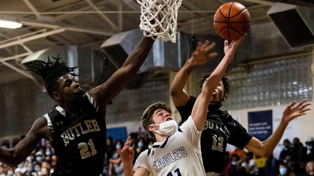 East MeckÕs Jordon Nevill, center, goes for a layup as Butler’s Peyton Scott, left, and Zion Mcduffie try and stop the play at the East Mecklenburg High School on Friday, January 28, 2022.