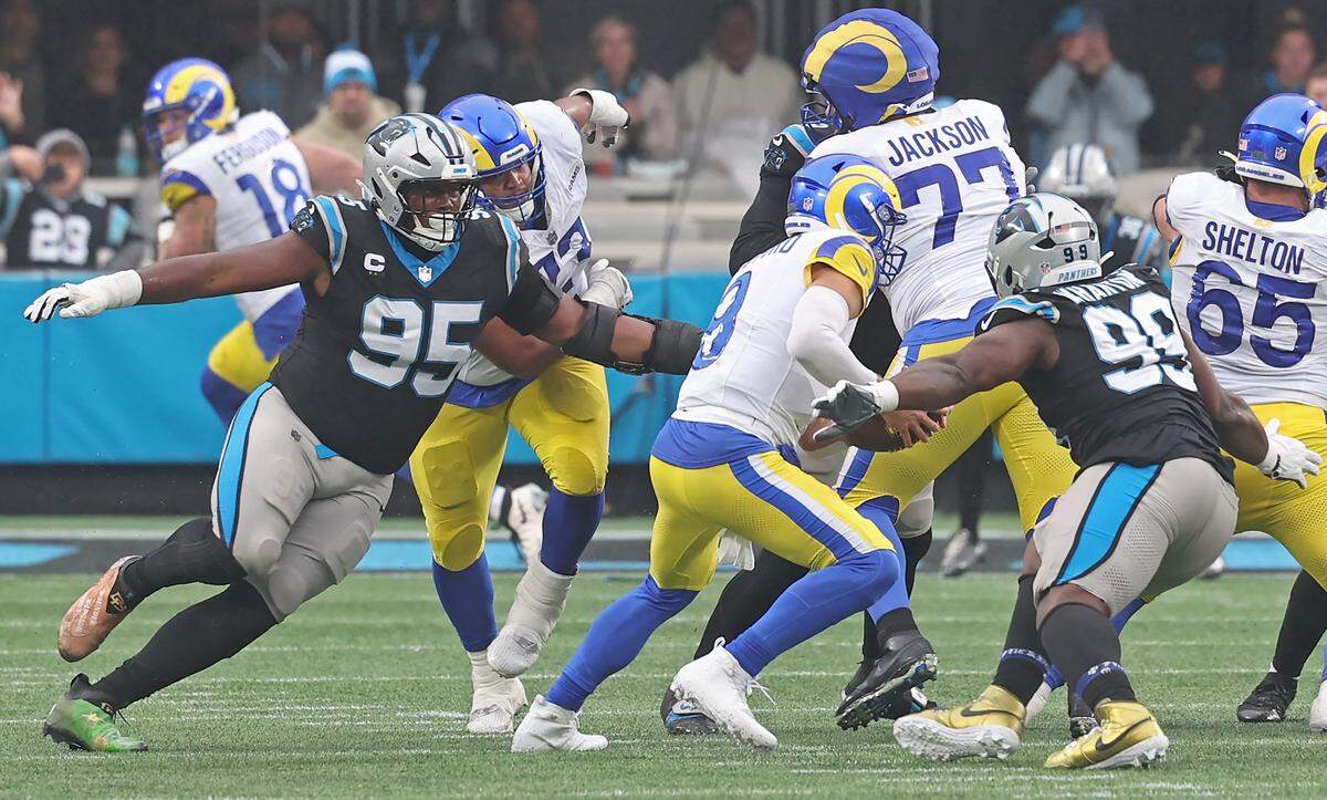 Carolina Panthers defensive tackle Derrick Brown, left, rushes Los Angeles Rams quarterback Matthew Stafford, center, in the pocket on Nov. 30, 2025, at Bank of America Stadium in Charlotte. Brown would cause Stafford to fumble the ball with the Panthers recovering. The Panthers defeated the Rams 31-28.