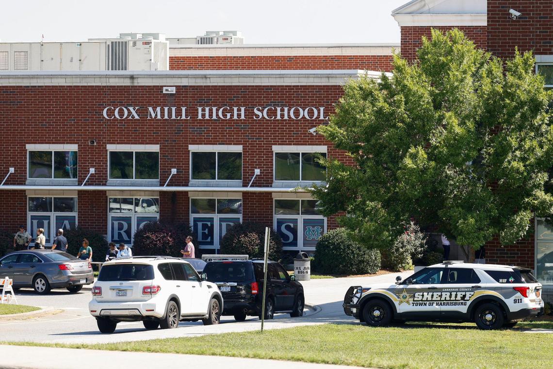 Law enforcement officers and students sit outside of Cox Mill High School in Concord, N.C., Tuesday, Sept. 20, 2022. A bomb threat was reported Cox Mill and other schools in the area on Tuesday,