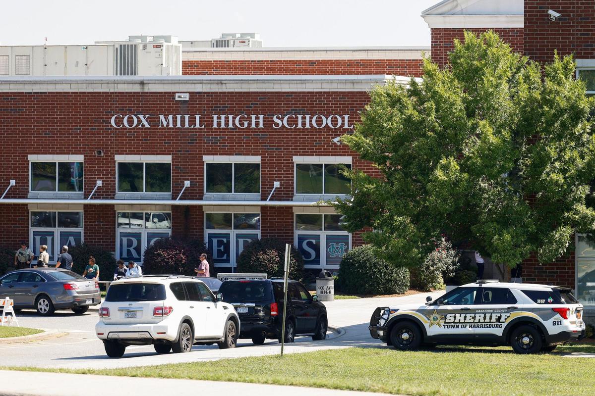 Law enforcement officers and students sit outside gather outside of Cox Mill High School in Concord, N.C., Tuesday, Sept. 20, 2022. A bomb threat was reported Cox Mill and other schools in the area on Tuesday,