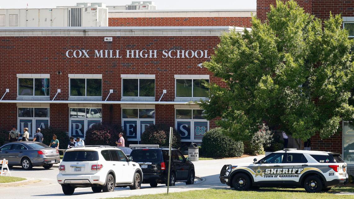 Law enforcement officers and students sit outside of Cox Mill High School in Concord, N.C., Tuesday, Sept. 20, 2022. A bomb threat was reported Cox Mill and other schools in the area on Tuesday,
