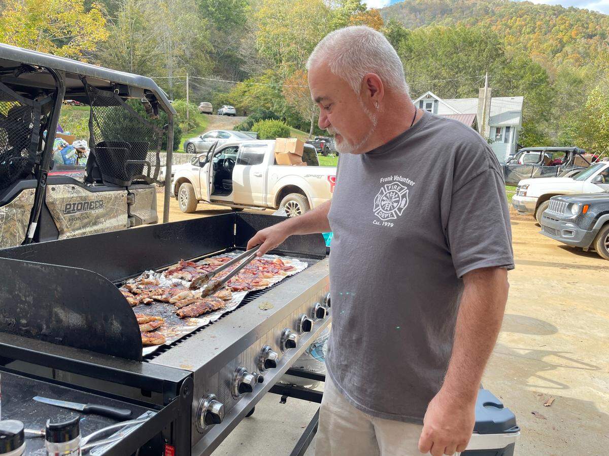 Teddy Bear grills barbecue chicken at Frank Volunteer Fire Department. Wind from a military Chinook will soon whip debris toward people and his fillets.