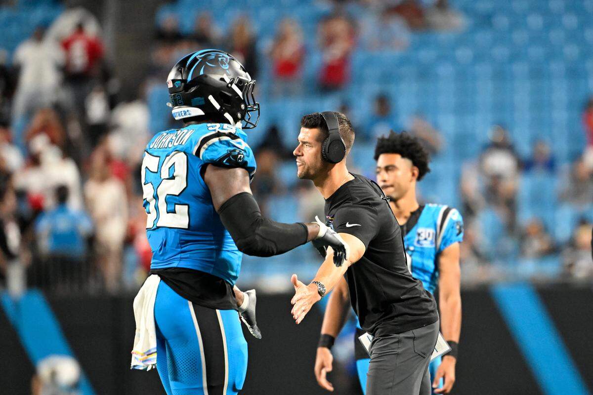 Carolina Panthers head coach Dave Canales congratulates linebacker DJ Johnson (52) as he comes off the field during a 2024 game at Bank of America Stadium.