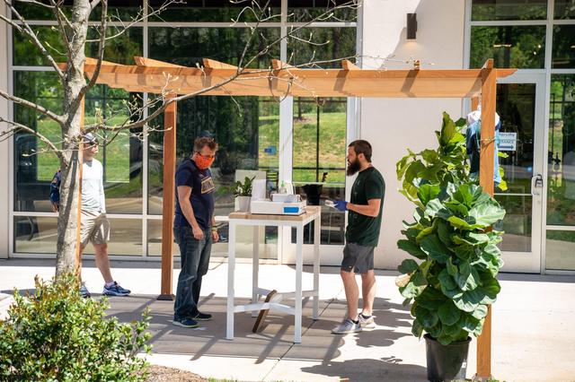 John Thomas serves a customer in front of Edge City Brewery to help with social distancing for to-go orders.