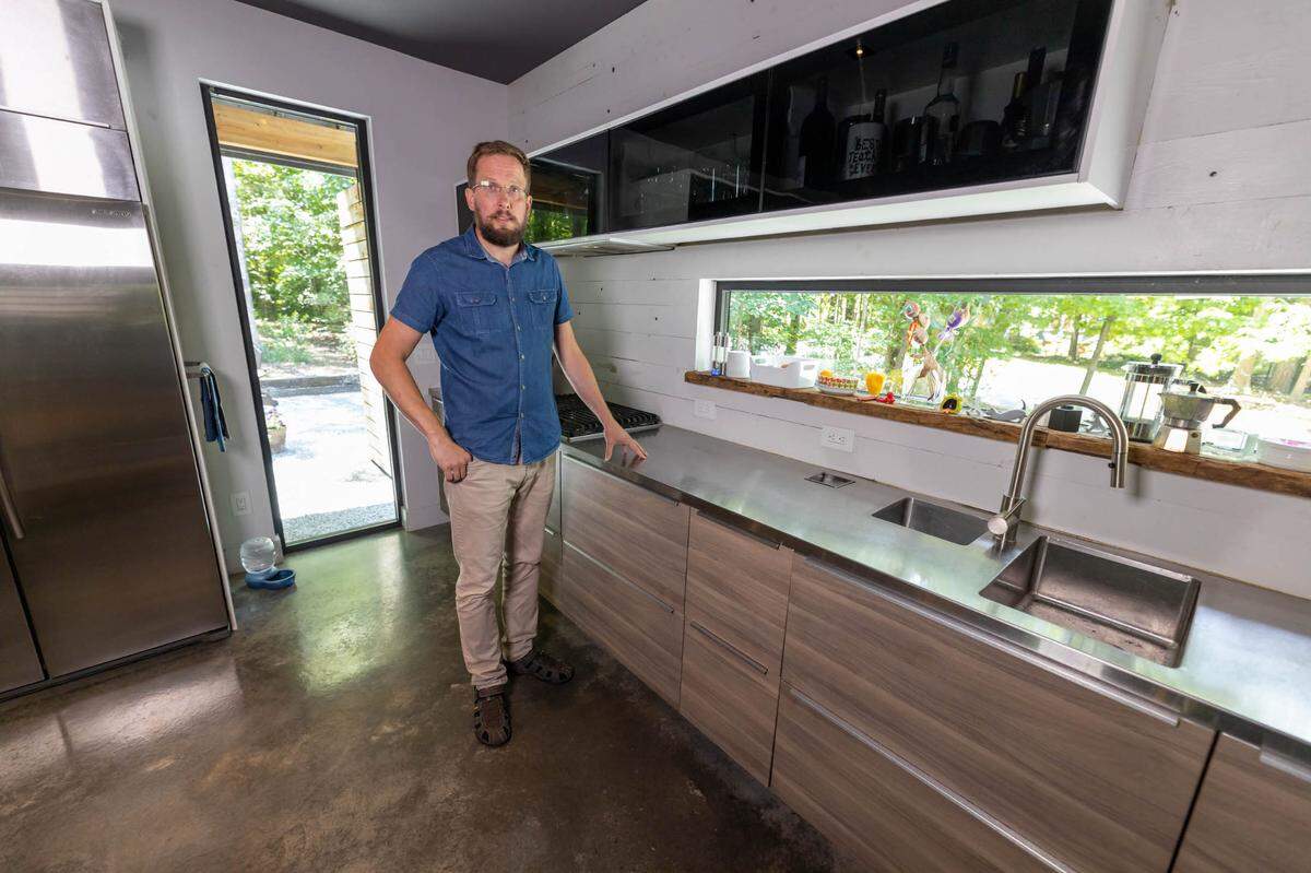 Toby Witte stands in his kitchen, which features discrete composting, a hidden spice rack and creative storage for dishes and utensils.