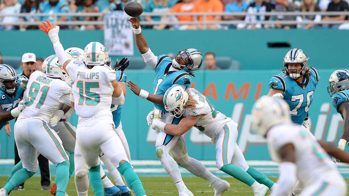 Carolina Panthers quarterback Cam Newton, center, is sacked by Miami Dolphins Andrew Van Ginkel, right, on a pass attempt during second quarter action at Hard Rock Stadium in Miami Gardens, Fla. on Sunday, November 28, 2021.