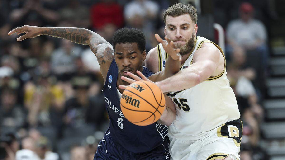 Oscar Cluff (45) of Purdue and Avantae Parker of Queens University battle for the ball during the first half of the teams’ first-round NCAA Men’s Tournament game at Enterprise Center on March 20, 2026 in St Louis, Missouri.
