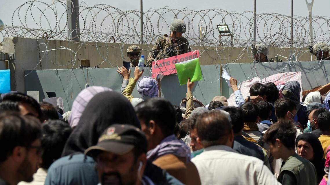 In this Aug. 26, 2021 file photo, a U.S. soldier holds a sign indicating a gate is closed as hundreds of people gather near an evacuation control checkpoint on the perimeter of the Hamid Karzai International Airport, in Kabul, Afghanistan.