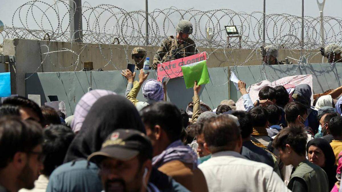 In this Aug. 26, 2021 file photo, a U.S. soldier holds a sign indicating a gate is closed as hundreds of people gather near an evacuation control checkpoint on the perimeter of the Hamid Karzai International Airport, in Kabul, Afghanistan.