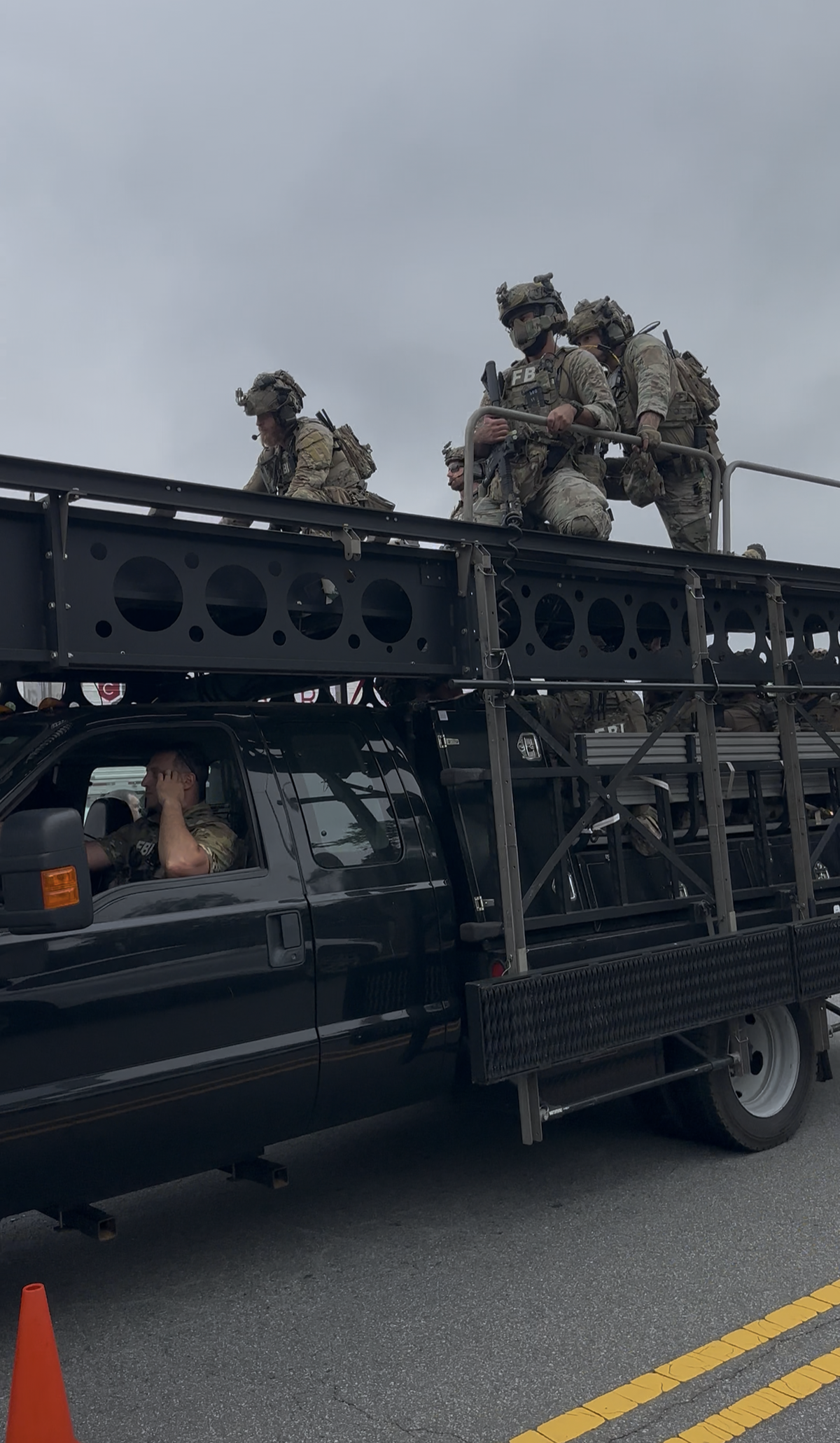 Armed FBI agents standing on top of an armored pickup truck as they left the scene of a joint law enforcement operation with CMPD in north Charlotte on Wednesday.