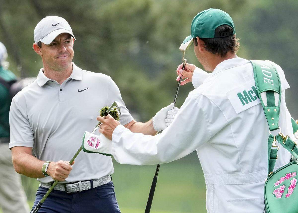 Rory McIlroy trades clubs with his caddie, Harry Diamond, as he walks the first fairway during the second round of The Masters golf tournament Friday.