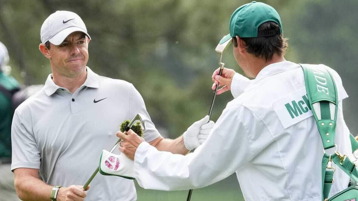 Rory McIlroy trades clubs with his caddie, Harry Diamond, as he walks the first fairway during the second round of The Masters golf tournament Friday.
