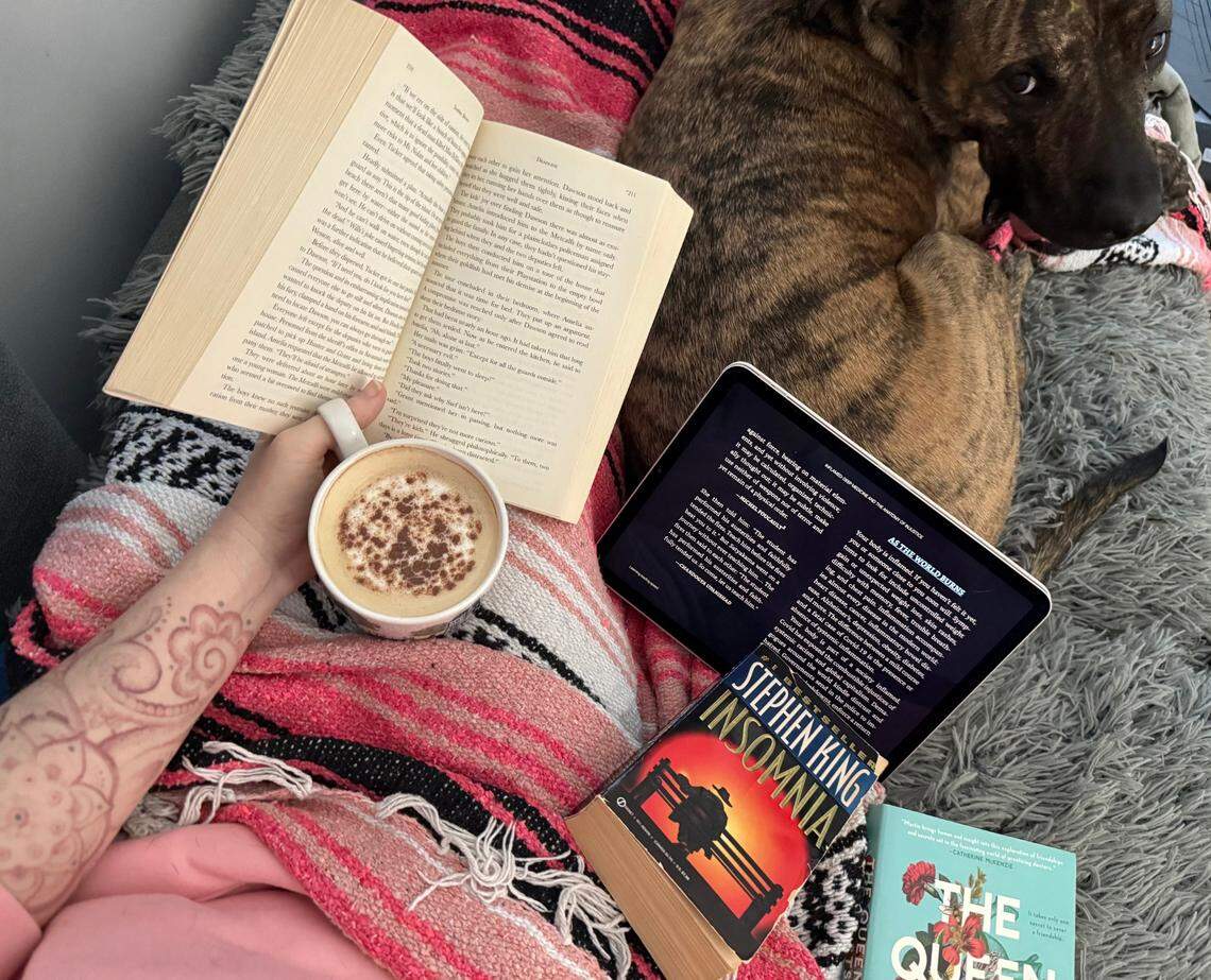 A pile of books rests alongside Charlie the dog, including the e-book version of “Inflamed: Deep Medicine and the Anatomy of Injustice” by Raj Patel and Rupa Marya.