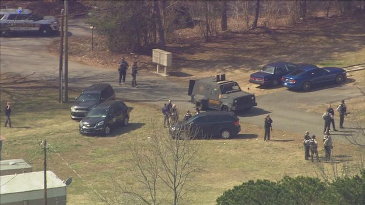 In this image taken from WSOC’s helicopter, law enforcement officials stand watch near a home in Lincoln County, NC, where a man barricaded himself with two hostages on Tuesday, Feb. 15, 2022. The standoff ended more than 13 hours later.