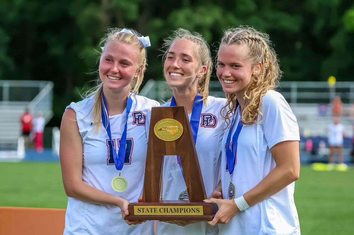 The three team captains of Providence Day proudly hold up the state championship trophy after clinching the title at the NCISAA girls soccer championship m at Charlotte Latin high school on May 17, 2025 in Charlotte, North Carolina