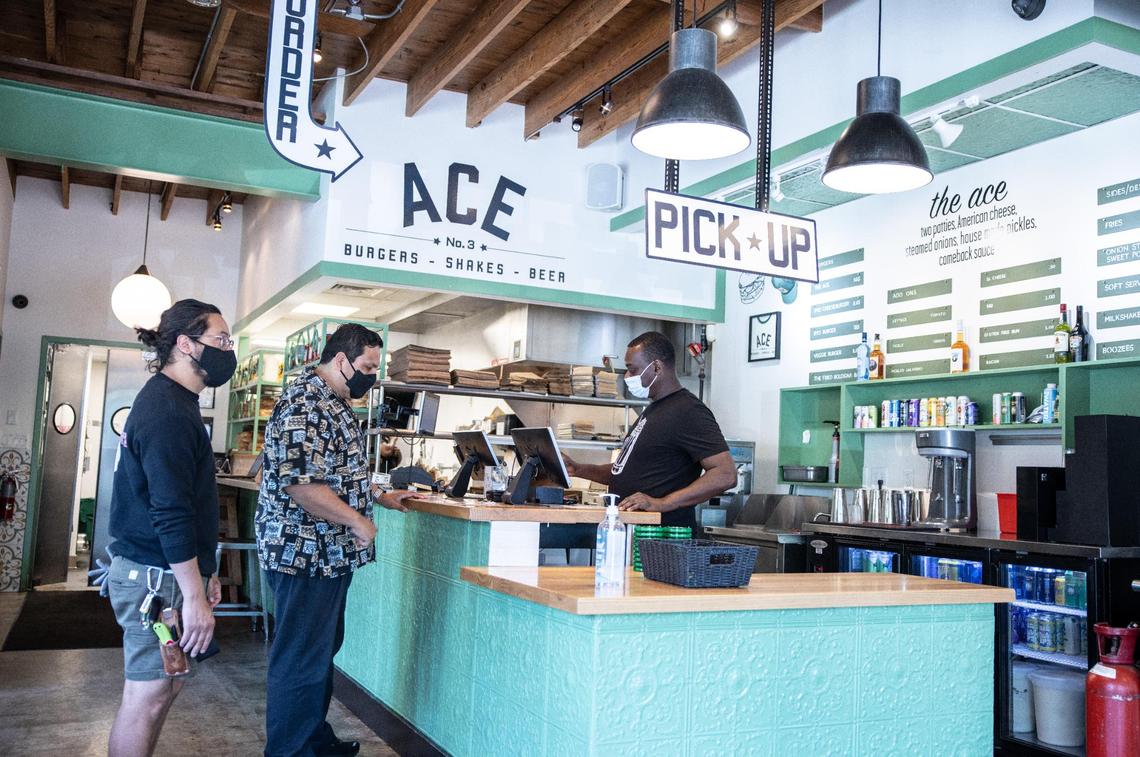 Customers wearing face masks line up to place orders Thursday at Ace No. 3 restaurant in Charlotte. The restaurant requires staff to wear masks because the majority of customers are still wearing them, co-owner Paul Manley.
