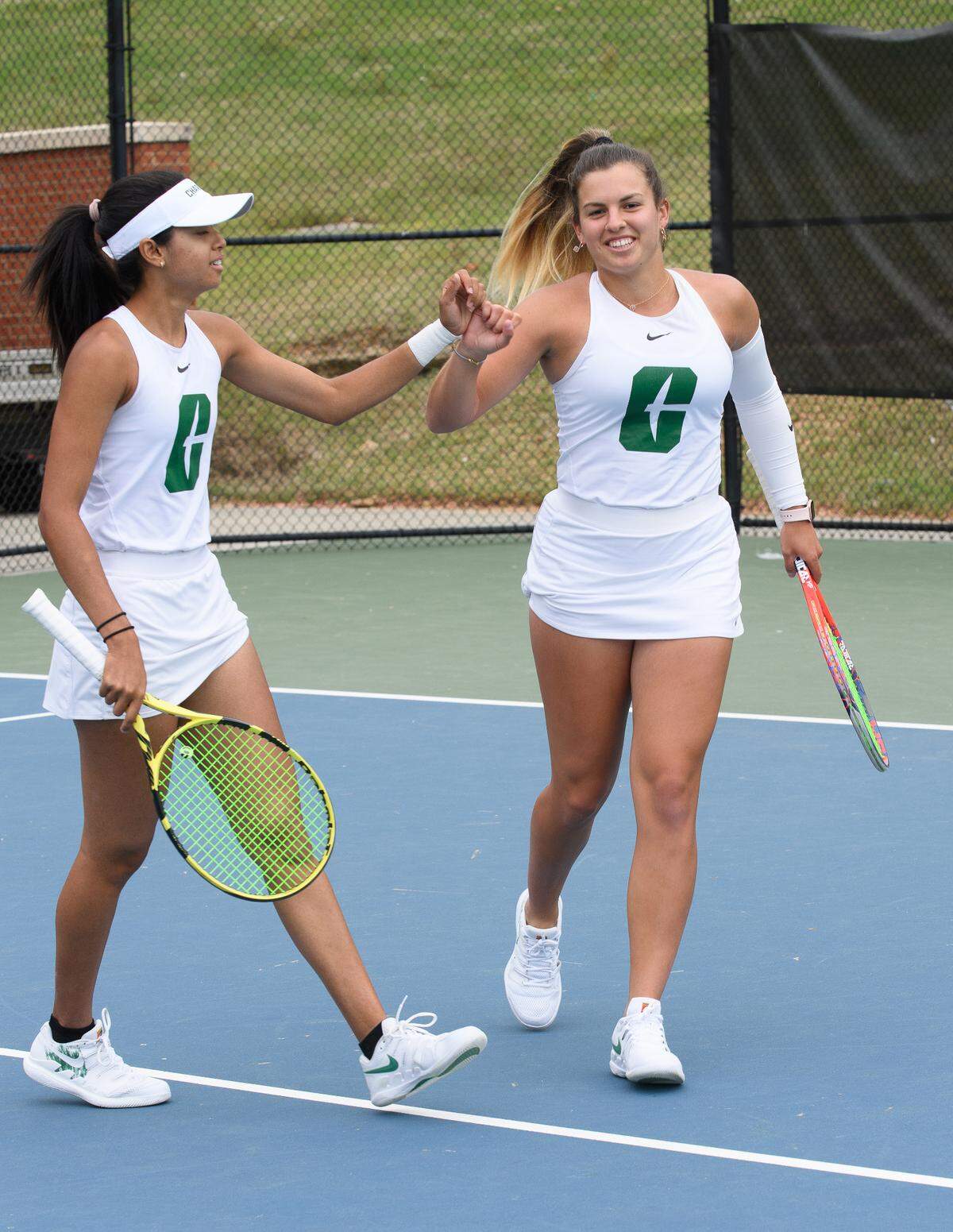 Charlotte’s Kaavya Sawhney (left) and Ruxi Schech celebrate after winning a point in 2021. The 49ers women’s tennis team reached No. 43 in the national rankings, an all-time high for the program.