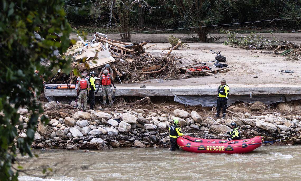 Two people and a dog are escorted to a rescue boat in Chimney Rock, N.C. on Sunday, September 29, 2024.