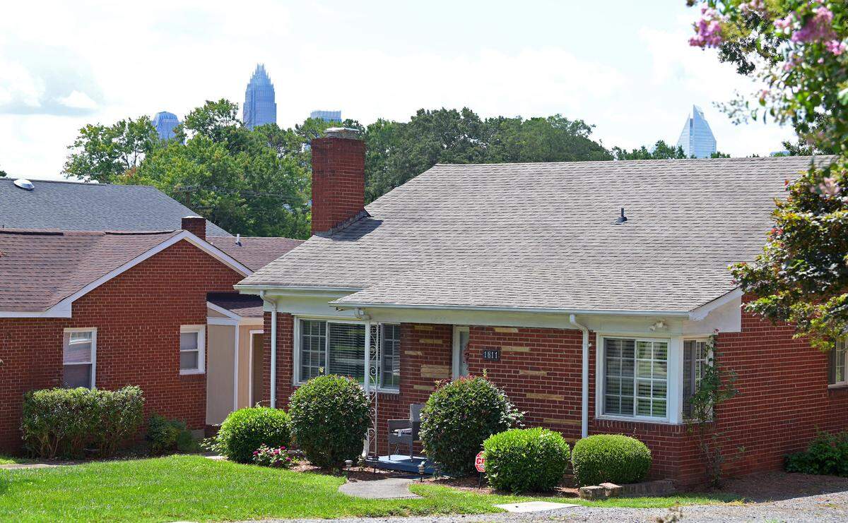 The Charlotte skyline peeks over the canopy behind homes along Patton Avenue in McCrorey Heights.