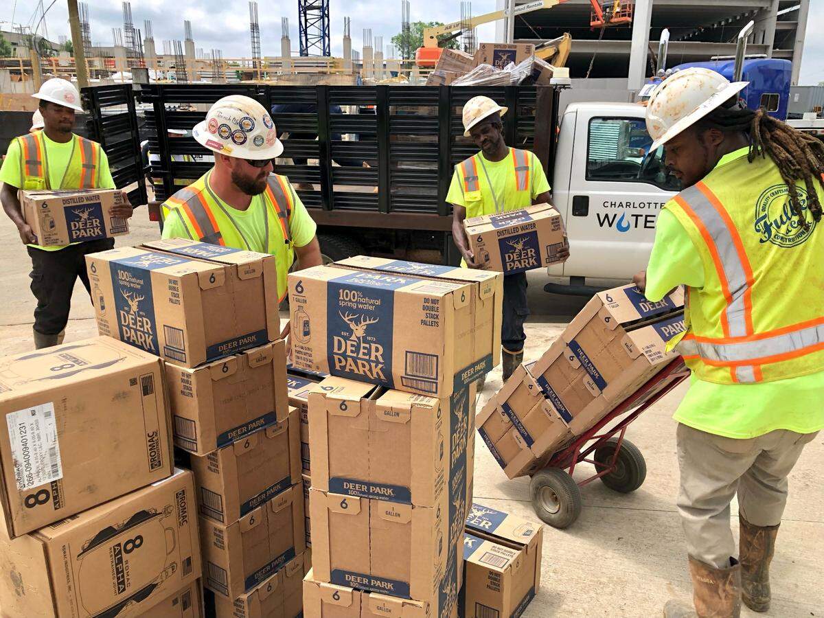 Charlotte Water employees unload boxes of water for residents near Duvanant and Hawkins streets in SouthEnd on Thursday, May 5, 2022. Workers are repairing to a damaged water main could take several hours to complete, according to the city utility.