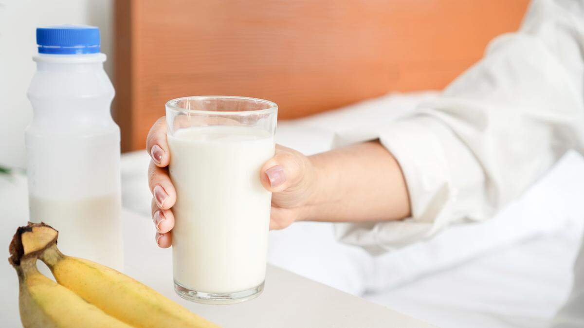 Close-Up of Woman's Hand Enjoying Milk and Banana as a Bedtime Snack, Embracing the Concept of Nutritious Eating