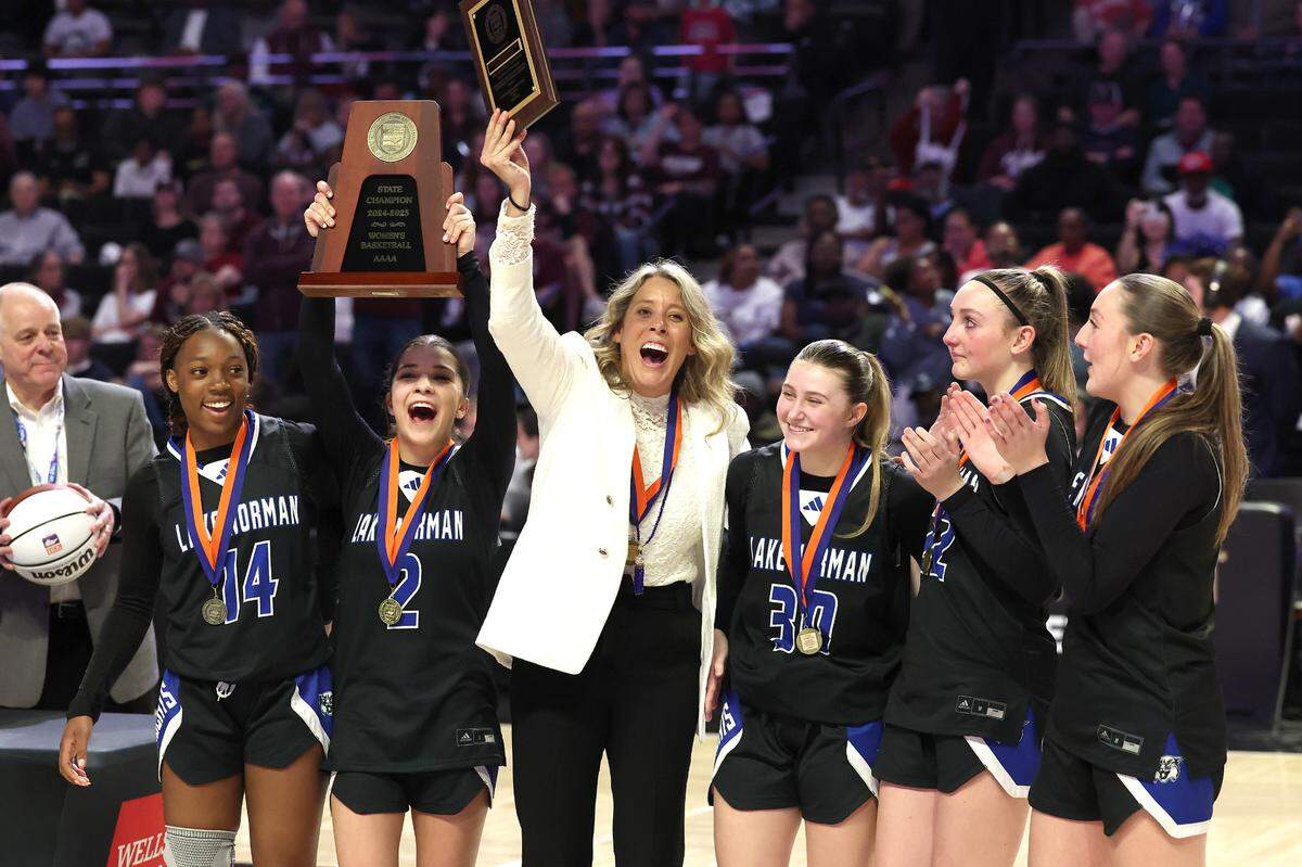 Lake Norman girls head basketball coach McKenzie Graham, center and members of the team celebrate their 43-41 victory over Wakefield in the girls NCHSAA 4A State Championship game on Saturday, March 15, 2025 at Lawrence Joel Veterans Memorial Coliseum in Winston-Salem, NC.