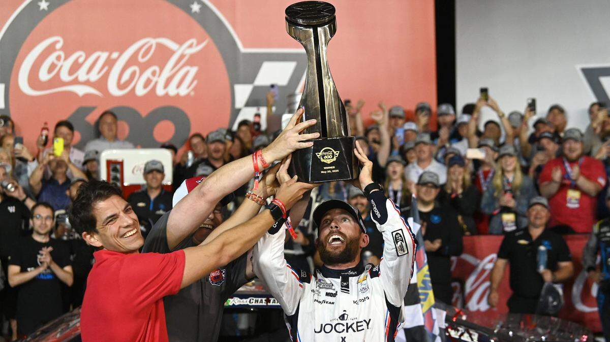 NASCAR Cup Series driver Ross Chastain gets some assistance lifting the Coca-Cola 600 trophy in Victory Lane at Charlotte Motor Speedway in Concord, NC on Sunday, May 25, 2025.