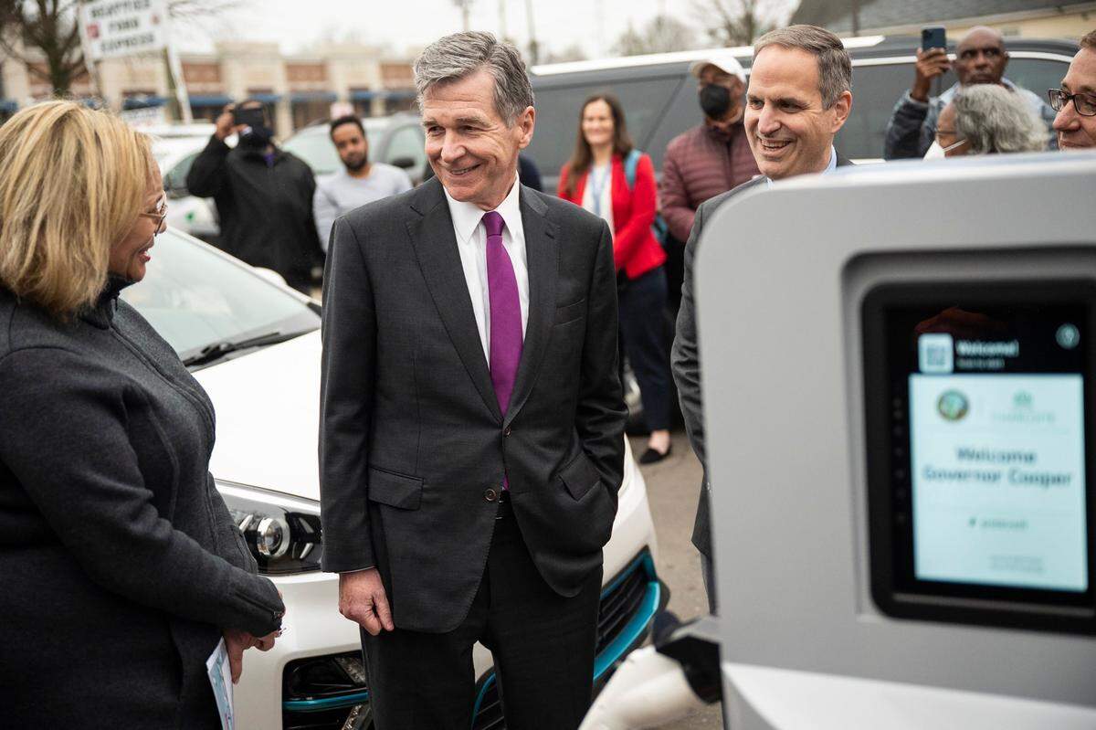 Governor Roy Cooper, second from left, shares a smile with Charlotte Mayor Vi Lyles, left, as they visit the PoleVolt EV charging station at The Ritz in Washington Heights on Thursday, February 24, 2022 in Charlotte, NC.