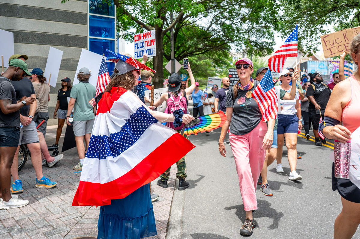 Katherine Wardwell fans protestors as they march down the street at the No Kings march and rally in Charlotte Saturday, June 14, 2025.