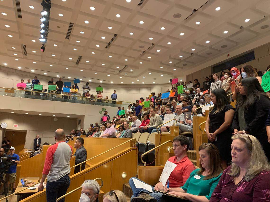 Vendors from the Central Flea Market hold signs for Charlotte City Council at a meeting Monday, July 11, 2022.