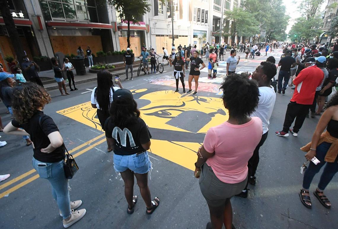 Supporters take photos of the Black Lives Matter mural on South Tryon Street, between Third and Fourth Streets, on Tuesday, June 9, 2020. Police are investigating after someone left what appear to be black tire marks over the entire length of the mural in uptown Charlotte.“