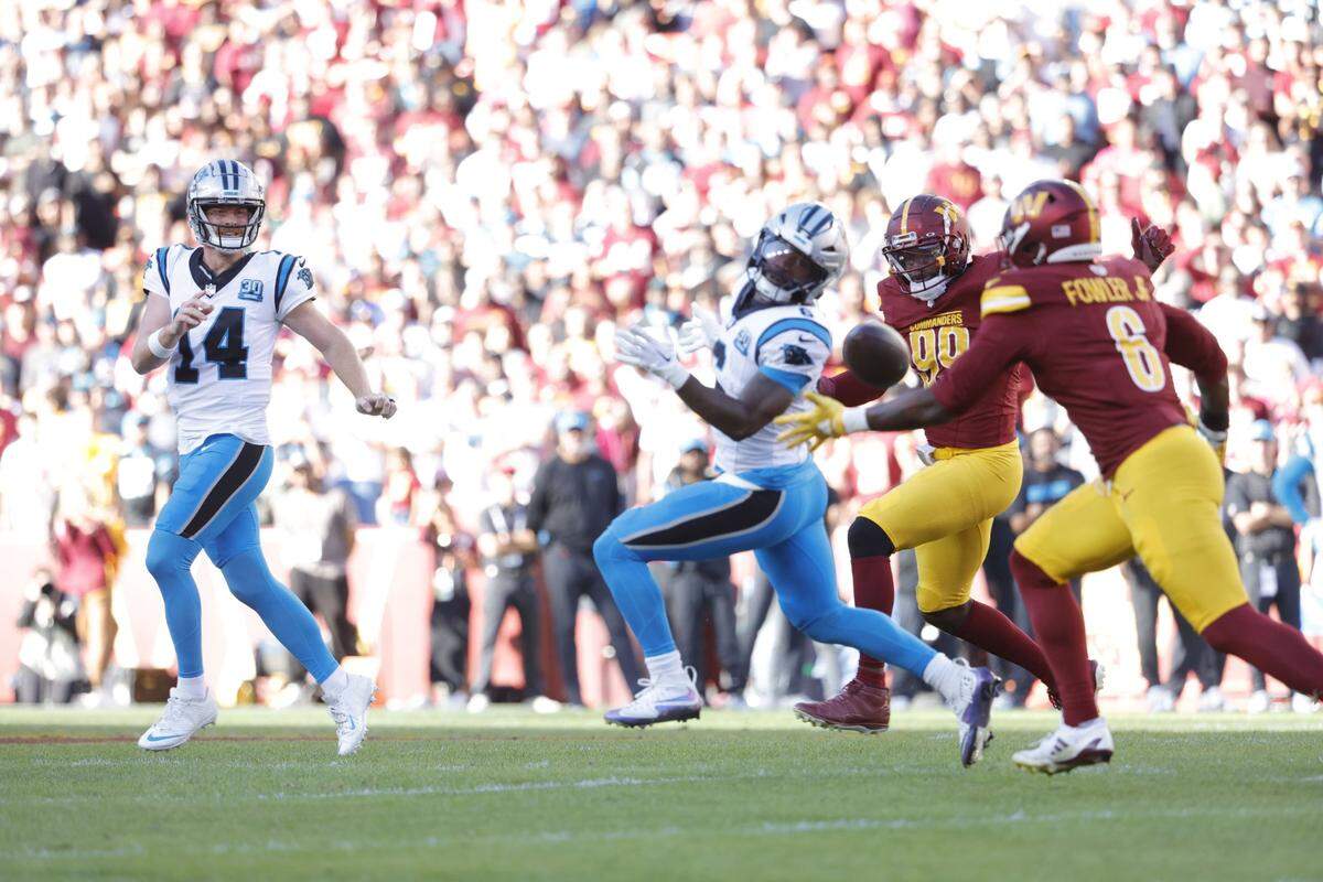 Oct 20, 2024; Landover, Maryland, USA; Carolina Panthers quarterback Andy Dalton (14) throws a pass intended for Panthers running back Miles Sanders (6) to Washington Commanders linebacker Dante Fowler Jr. (6) during the first quarter at Northwest Stadium. Mandatory Credit: Amber Searls-Imagn Images