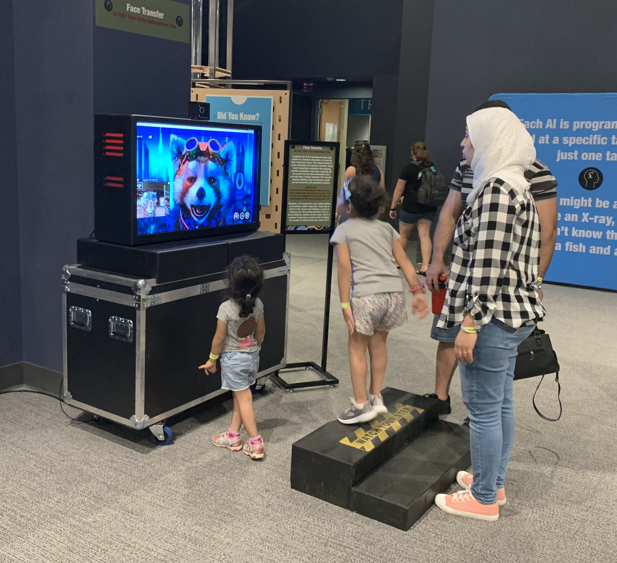 A family visiting “Artificial Intelligence: Your Mind & The Machine” at the Orlando Science Center engages with an AI face transfer display. The technology is frequently used to turn real faces into models for animated characters in films and video games. The exhibit is debuting at Discovery Place in uptown Charlotte.