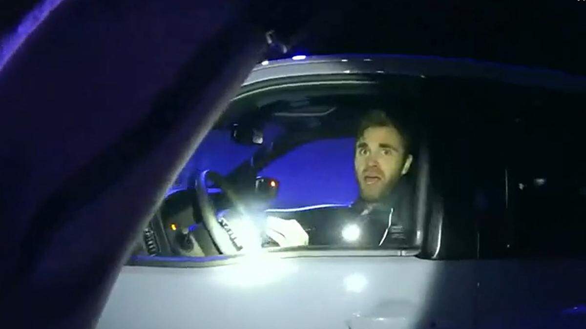 In this image from video provided to WSOC, Brandon Combs looks at now-former Officer Timothy Larson from inside a pickup truck at a Nissan dealership in Concord, N.C., on Feb. 13, 2022. Moments later, Combs fled the pickup and jumped into Larson’s police SUV.