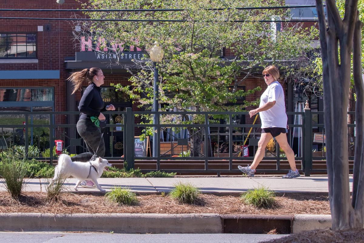 A woman and her dog jog along a path in South End on Thursday, April 3, 2020.