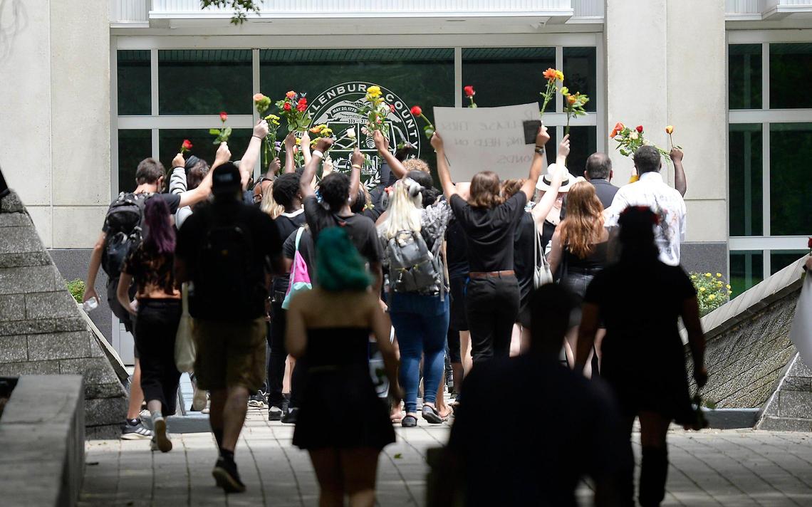 Participants in a protest organized by Decarcerate Mecklenburg, called Funeral Friday, carry flowers and boxes representing coffins during part of a memorial to honor those who have died from coronavirus while being incarcerated, on Friday, August 7, 2020.