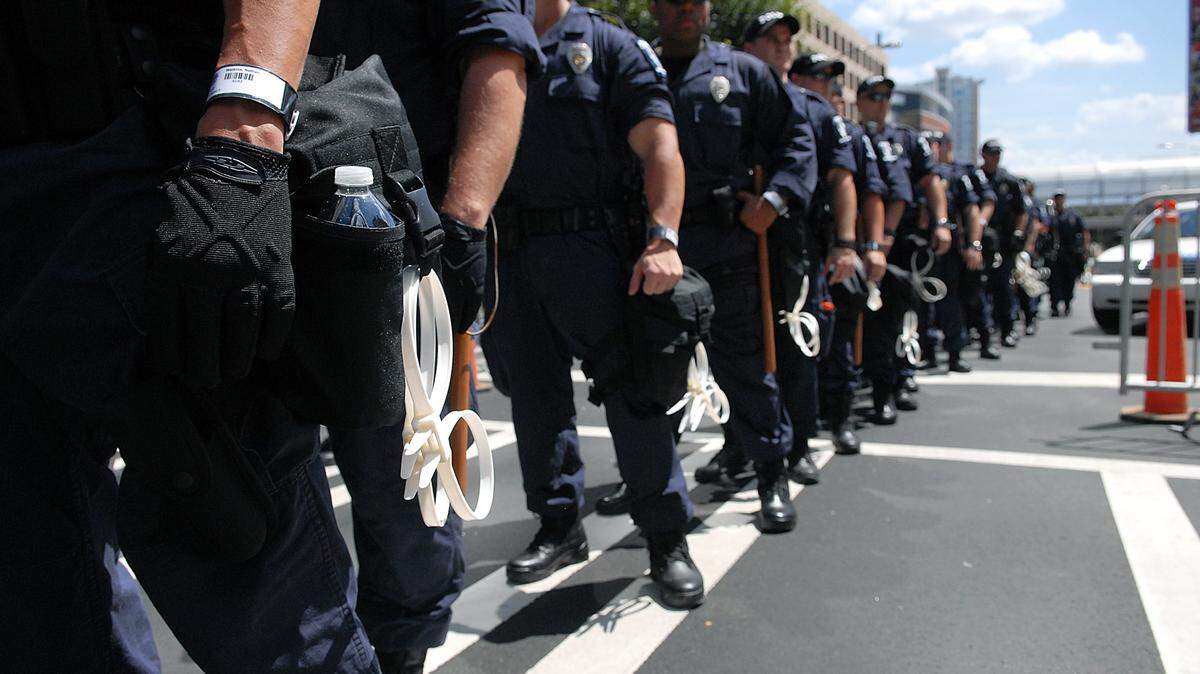CMPD police officers, ready with plastic handcuffs, wait to line the protest route at the corner of Trade and College Streets for the DNC in 2012.