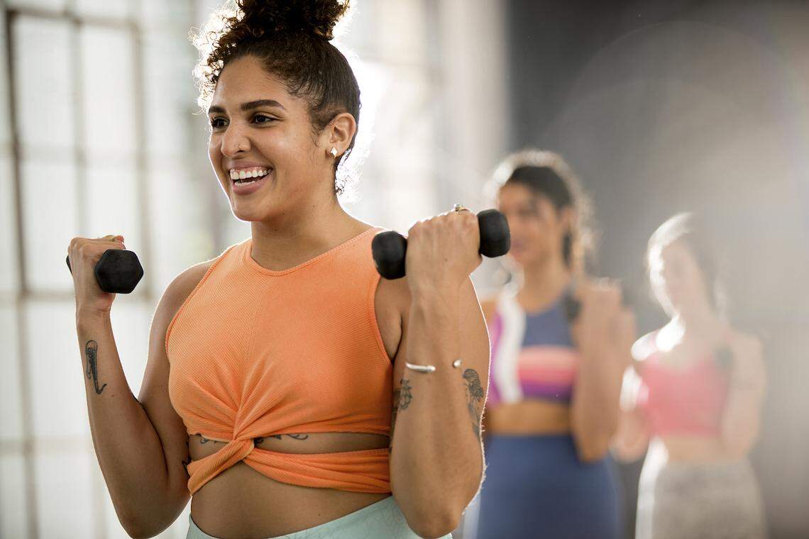 A group of people in a fitness class performing bicep curls while holding small dumbbells.