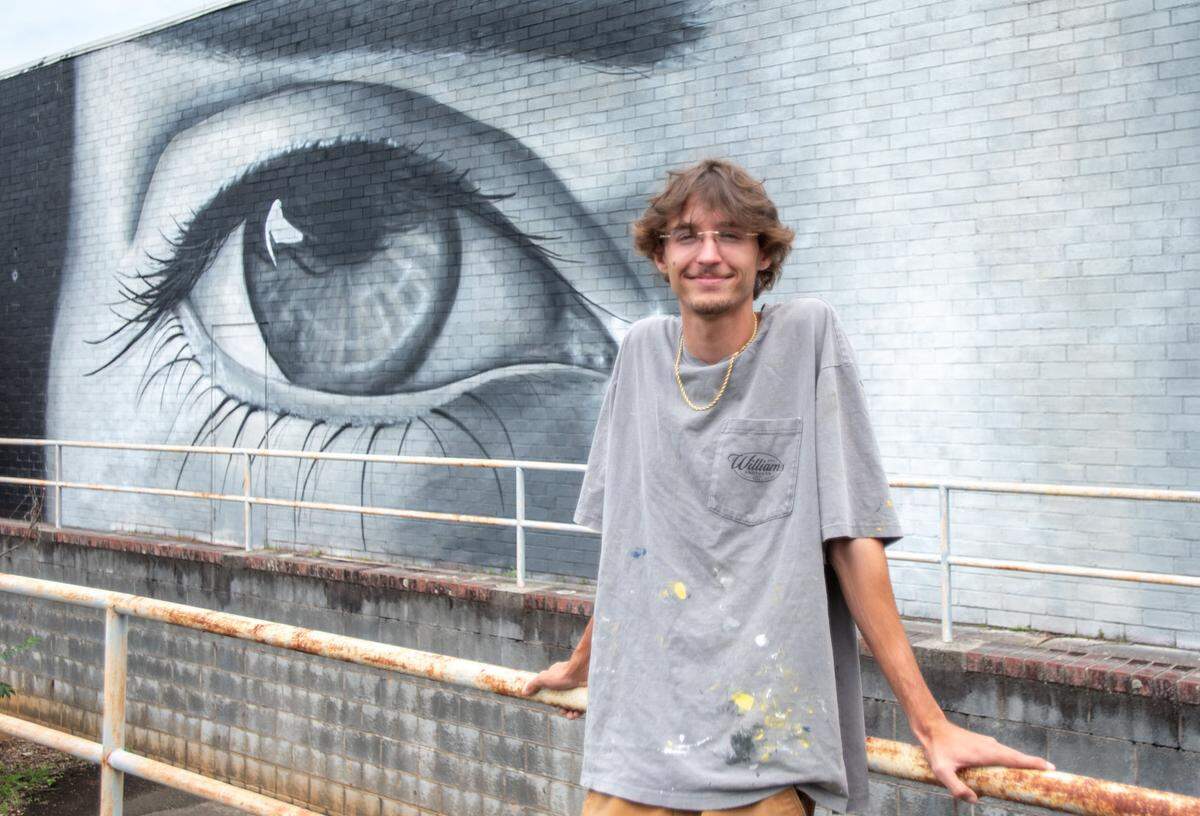 Albemarle native muralist Eli Williams poses in front of his work on Pee Dee Avenue in Albemarle, NC, on Tuesday, June 10, 2025. After completing their art degrees, Eli and his brother Jack returned to Albemarle to manage their business, WMSBrothers.