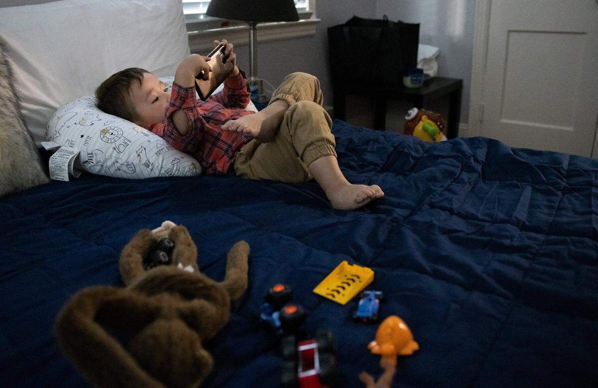 Samim, 2, plays with a smartphone in Charlotte, on Nov. 10, 2021. He and his family fled Afghanistan in August and join thousands of people, many of whom worked as interpreters for the U.S. military, who must resettle due to threats from the Taliban.