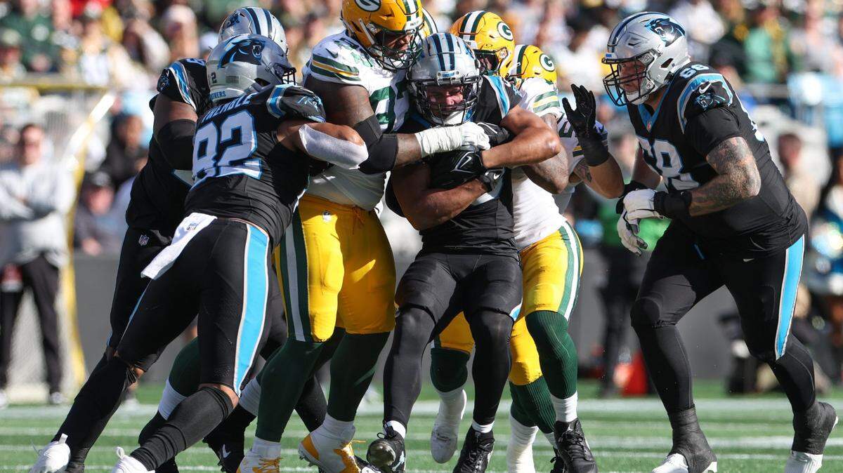 Carolina Panthers running back Chuba Hubbard (30) is flanked by Packers defense during the game at Bank of America Stadium on Sunday, December 24, 2023.
