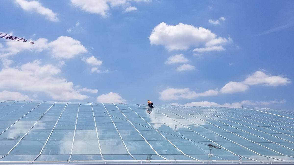 A construction worker atop a glass canopy at Charlotte Douglas International Airport. The skybridges are under that 146,000-square-foot canopy, providing passengers convenience and weather protection.