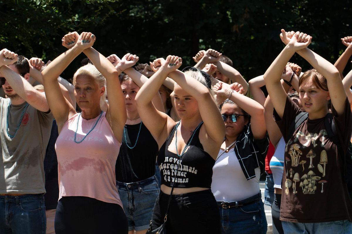 Myers Park alumni Nikki Wombwell (center) is joined by the crowd as they hold up their arms in solidarity at a protest against sexual assault on Tuesday, June 29, 2021.