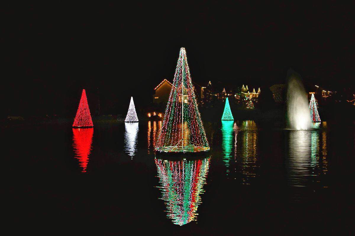 Illuminated trees’ reflection shines on the lake in McAdenville.